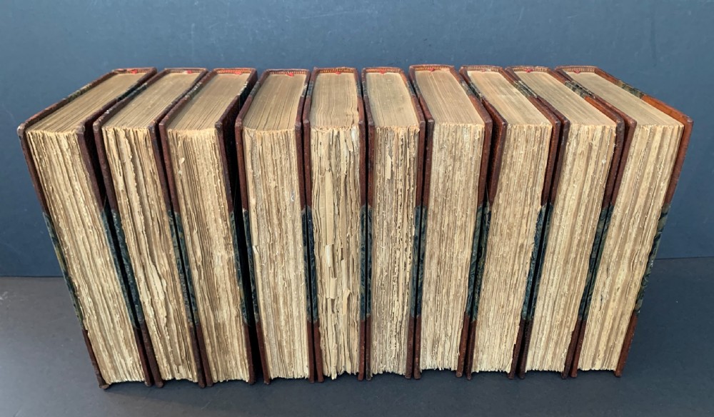 A collection of ten matching antique tan leather-bound books standing upright with gold leaf lettering on their spines. View III