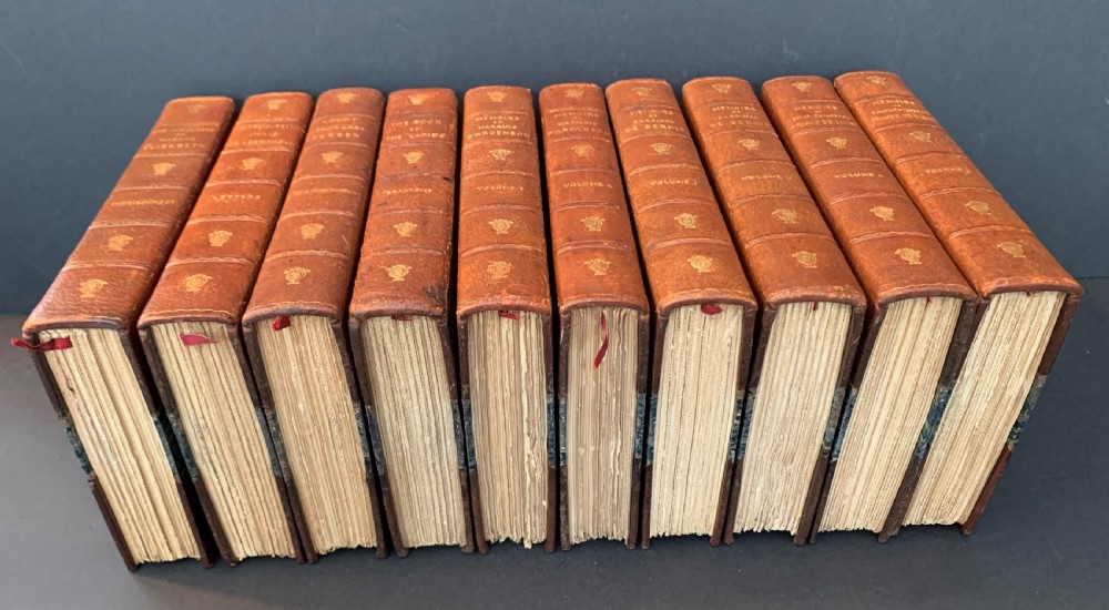 A collection of ten matching antique tan leather-bound books standing upright with gold leaf lettering on their spines. View IV