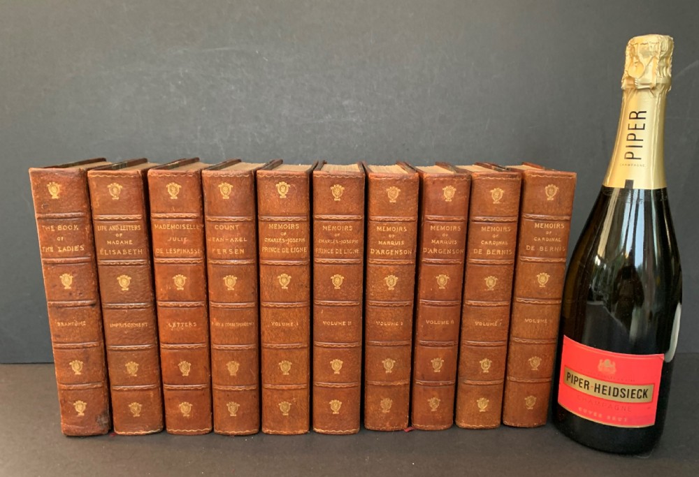 A collection of ten matching antique tan leather-bound books standing upright with gold leaf lettering on their spines. View XVI