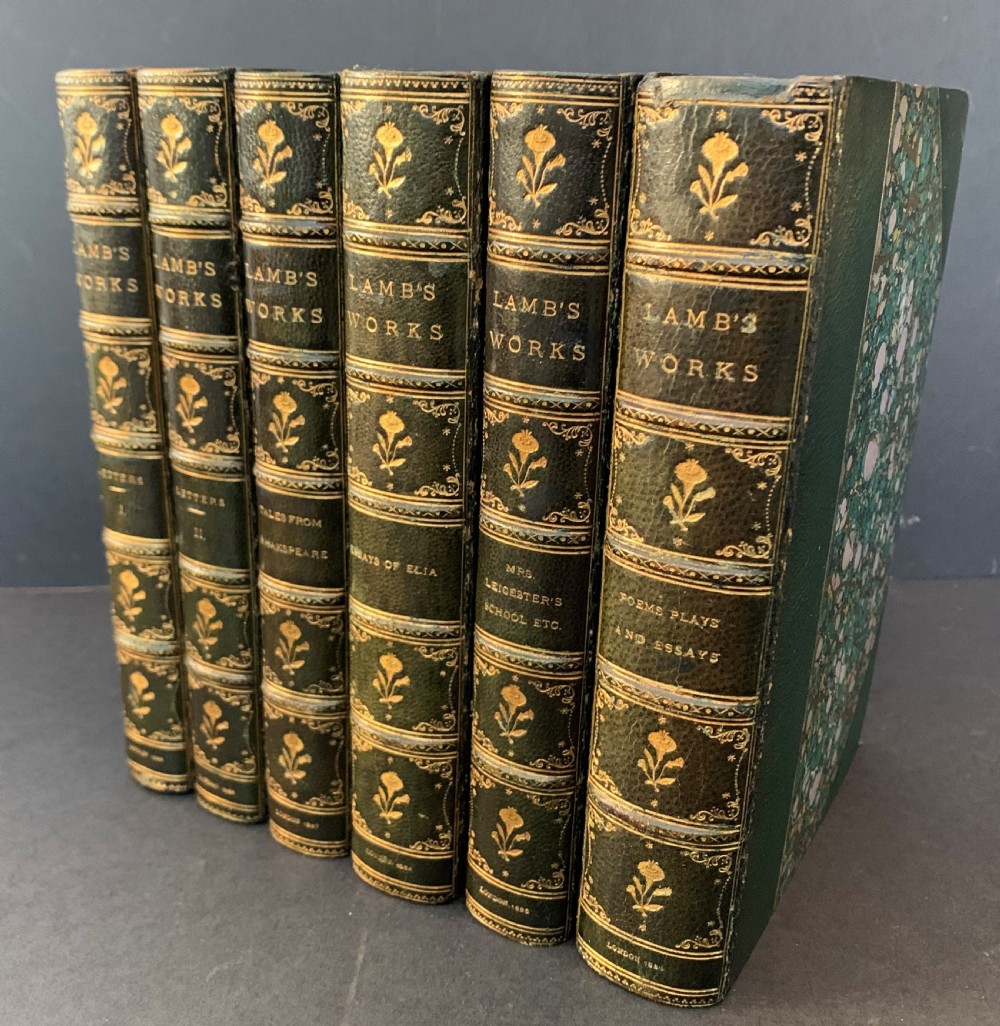 A six-volume set of late Victorian books featuring dark green leather spines with gilt floral tooling and title lettering alongside marbled paper boards.