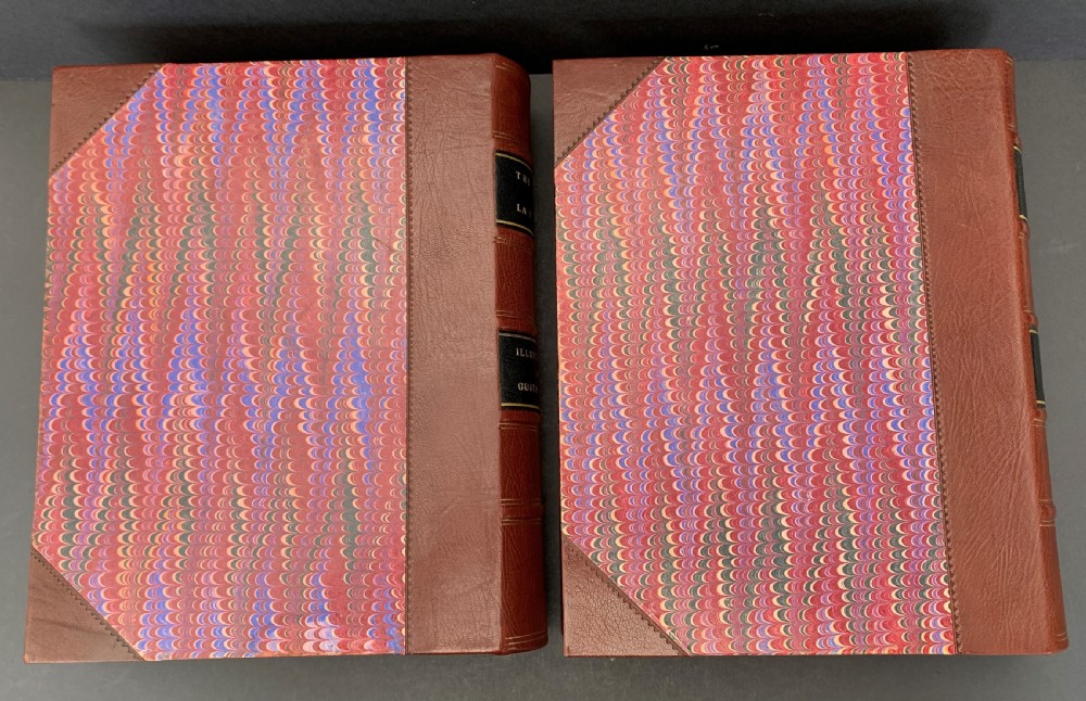 Pair of Victorian half-leather bound books with warm brown spines, gilt lettering on black labels, and red and blue marbled paper boards. View II