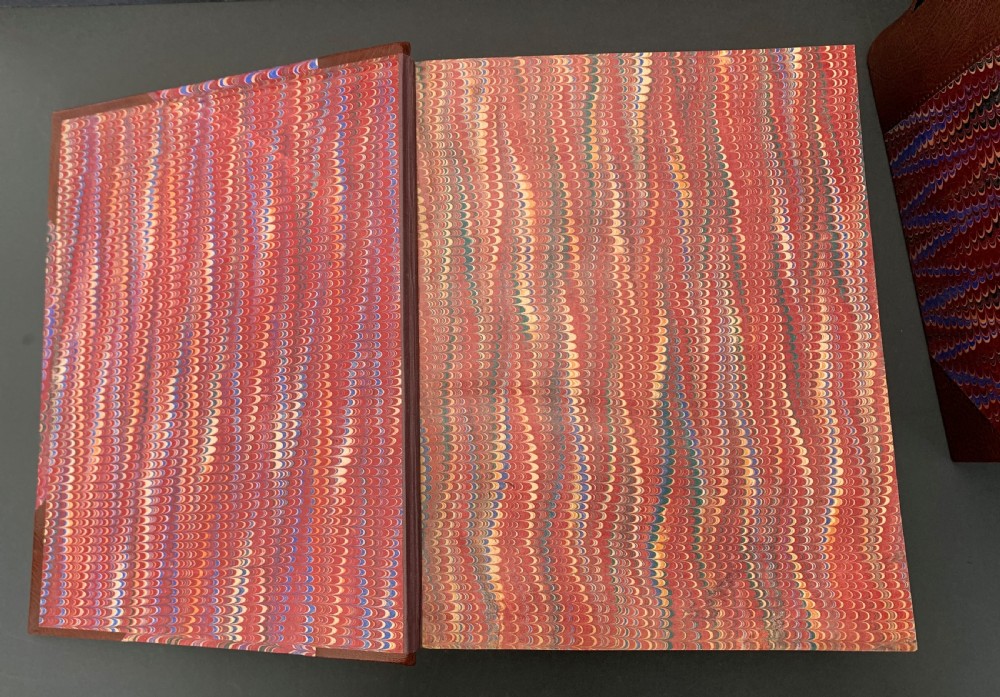 Pair of Victorian half-leather bound books with warm brown spines, gilt lettering on black labels, and red and blue marbled paper boards. View V