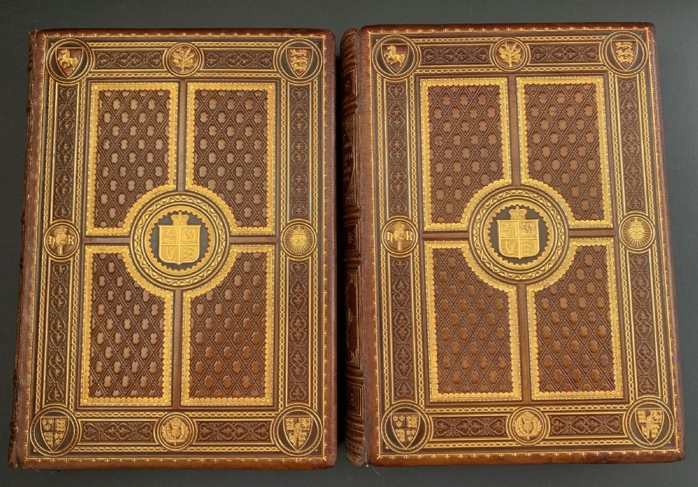 A pair of Victorian leather-bound books featuring gold leaf tooling, crest motifs, and embossed geometric patterns on the brown boards and spines. View III