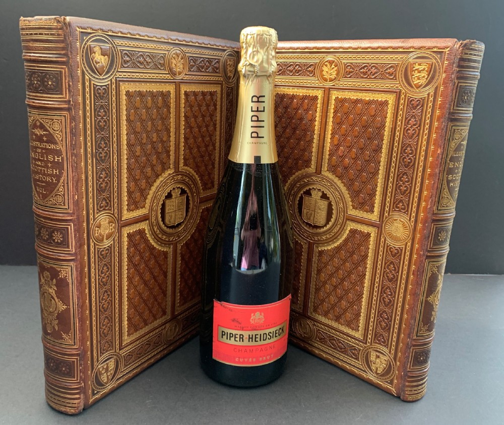 A pair of Victorian leather-bound books featuring gold leaf tooling, crest motifs, and embossed geometric patterns on the brown boards and spines. View XIX