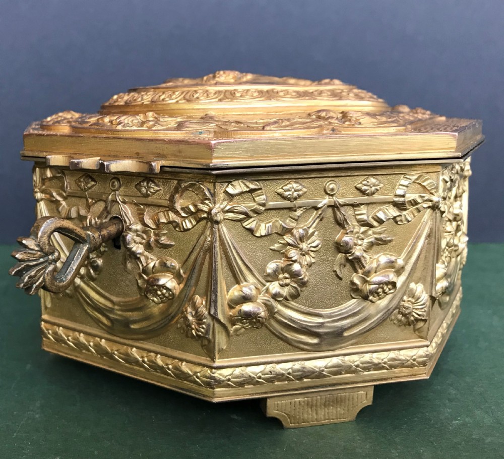 An octagonal French gilded copper jewellery casket decorated with detailed relief carvings of cherubs and floral garlands. View II