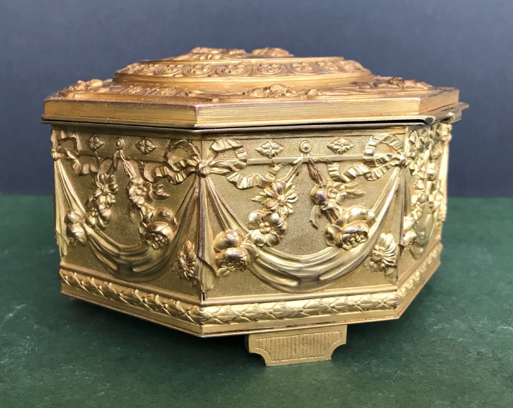 An octagonal French gilded copper jewellery casket decorated with detailed relief carvings of cherubs and floral garlands. View III