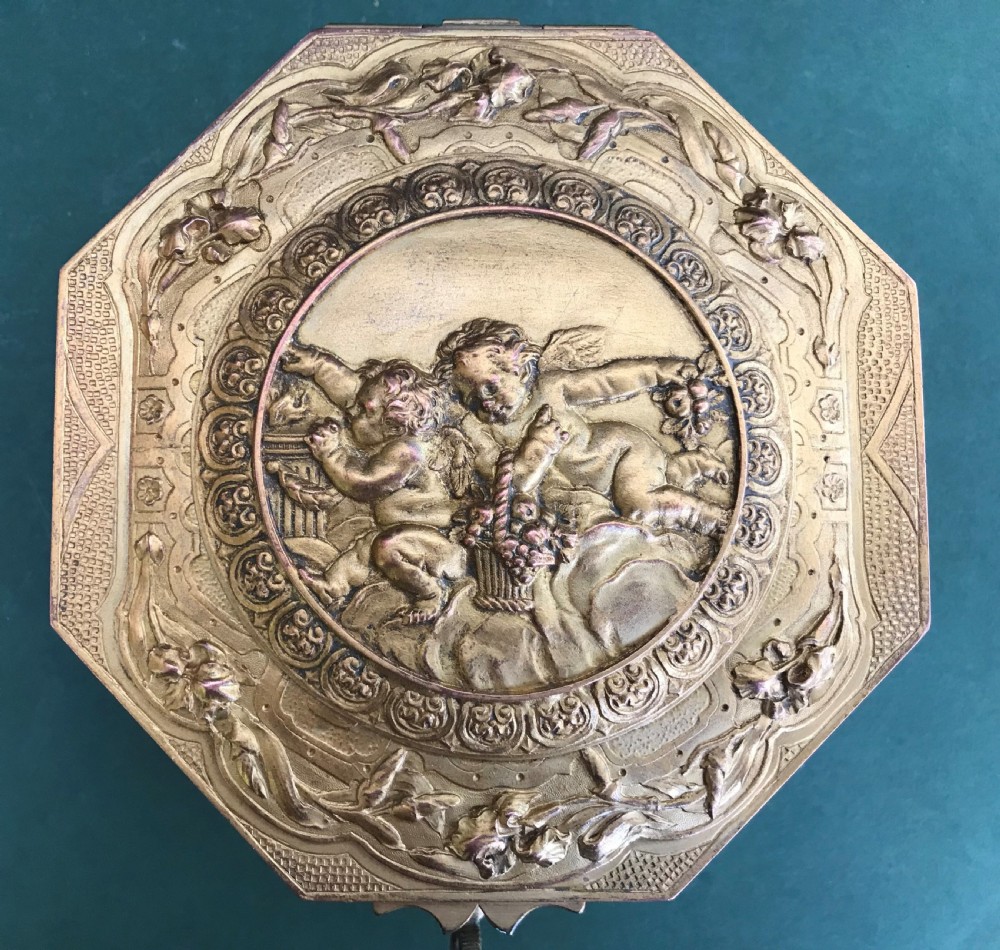 An octagonal French gilded copper jewellery casket decorated with detailed relief carvings of cherubs and floral garlands. View V