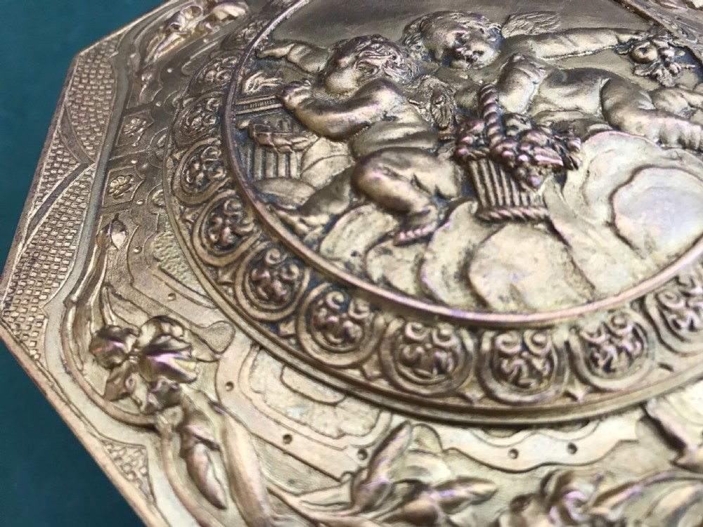 An octagonal French gilded copper jewellery casket decorated with detailed relief carvings of cherubs and floral garlands. View VI