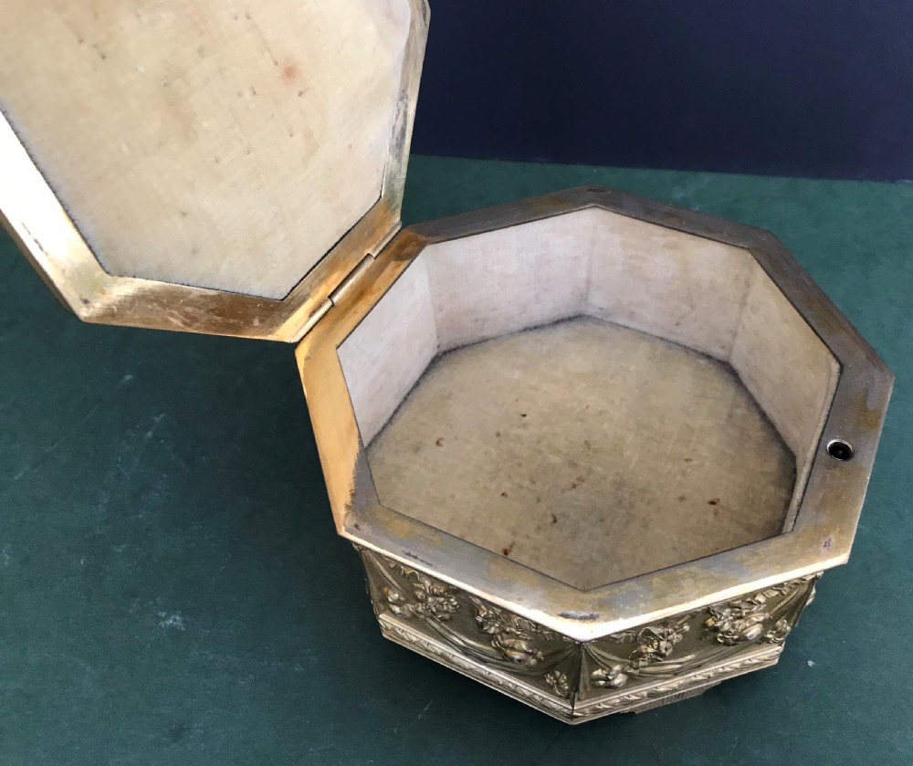 An octagonal French gilded copper jewellery casket decorated with detailed relief carvings of cherubs and floral garlands. View VII