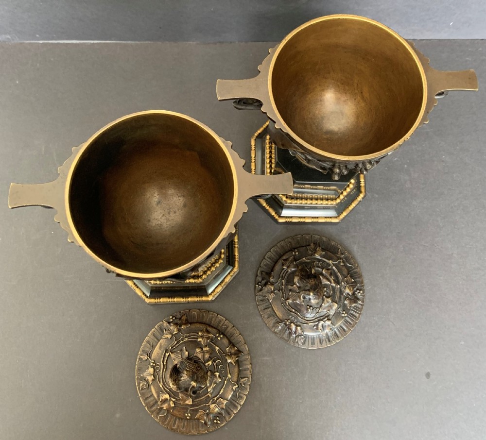 A pair of Victorian cast bronze lidded urns featuring foliage reliefs and bird finials, mounted on octagonal black marble plinths. View III