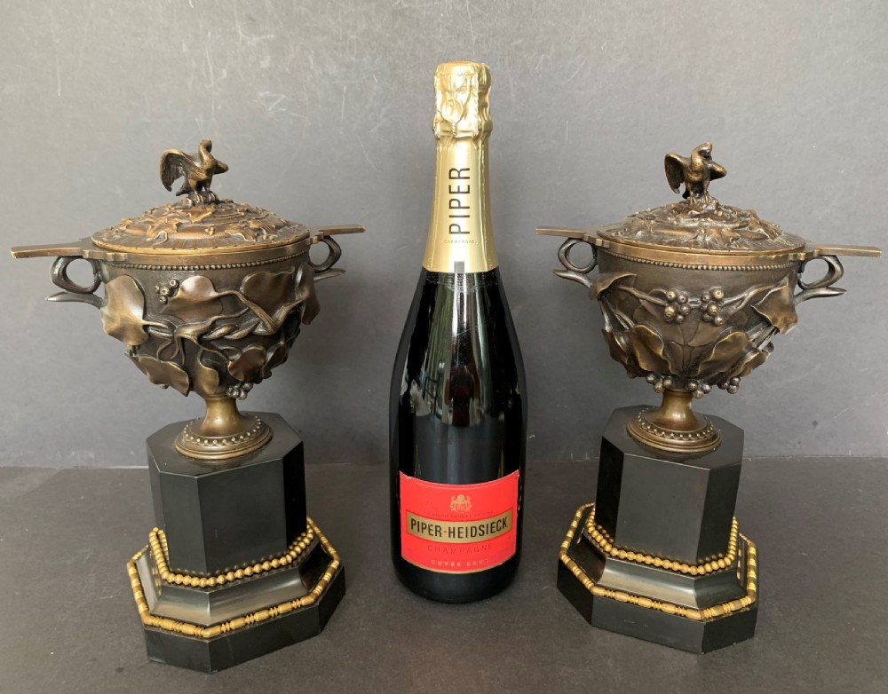 A pair of Victorian cast bronze lidded urns featuring foliage reliefs and bird finials, mounted on octagonal black marble plinths. View VII