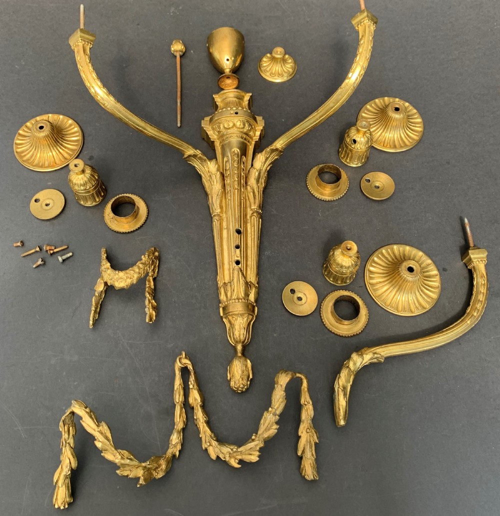A pair of French gilt bronze wall lights featuring three curving candle branches decorated with leaf swags and topped with urn backplates. View II