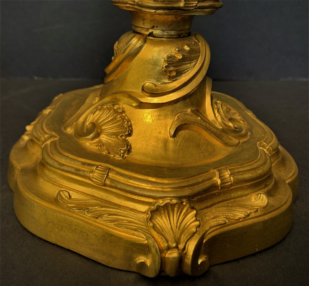 A pair of 19th-century French ormolu candlesticks featuring intricate acanthus leaf carving, rocaille shell motifs, and a gilded finish. View II