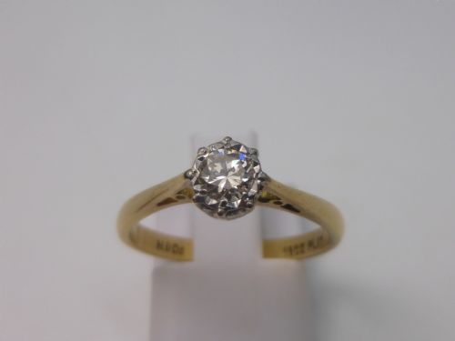 fig 1. A yellow gold solitaire ring featuring a single round brilliant-cut diamond held in a white metal claw setting.