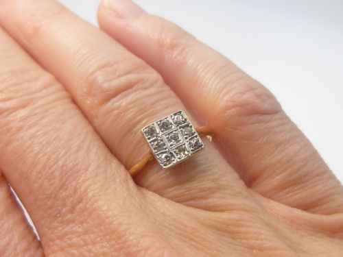 fig 1. An Edwardian ring featuring a square setting containing nine diamonds in a three-by-three grid atop an 18ct yellow gold band.
