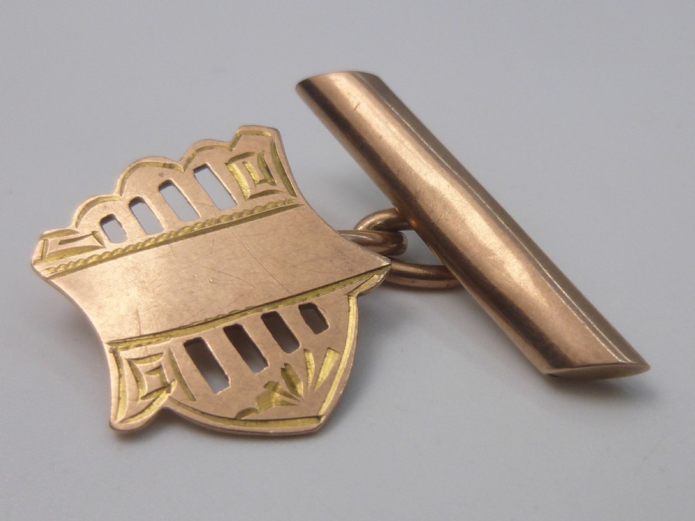 A pair of Edwardian 9ct rose gold cufflinks featuring pierced shield-shaped faces linked to torpedo backs. View IV