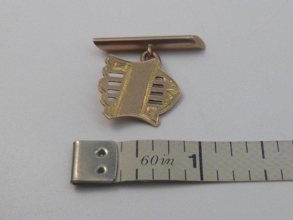 A pair of Edwardian 9ct rose gold cufflinks featuring pierced shield-shaped faces linked to torpedo backs. View V