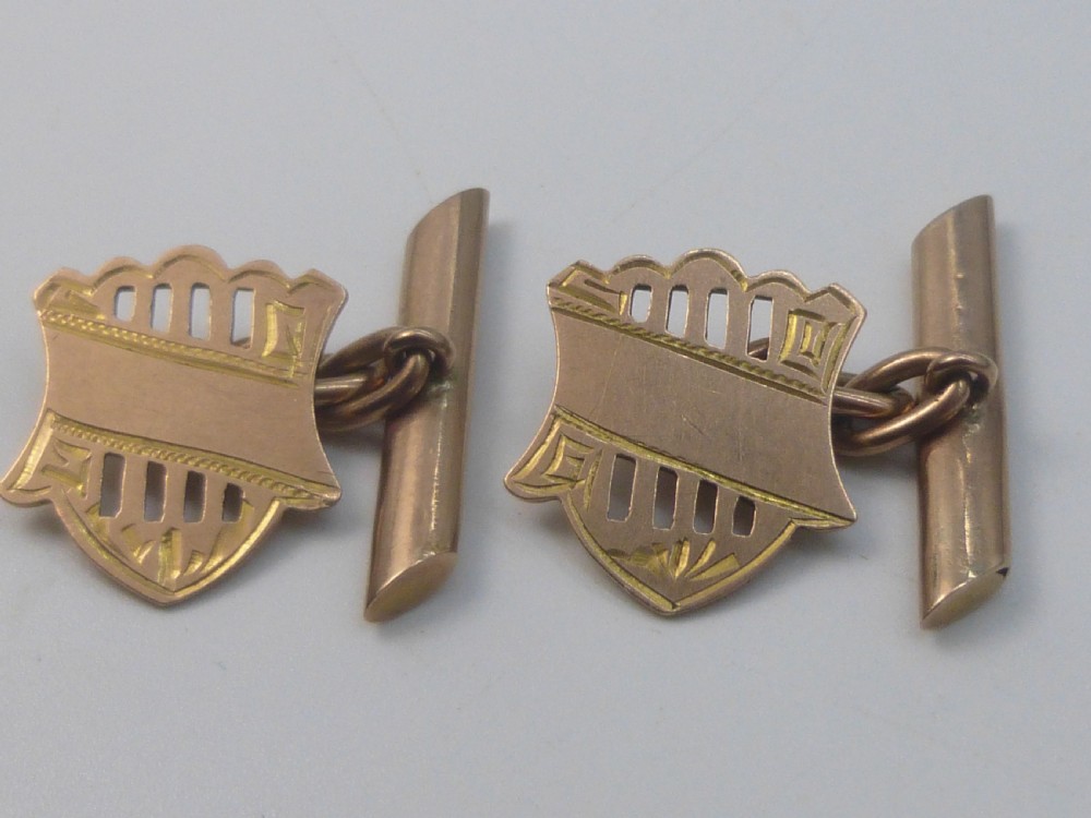 A pair of Edwardian 9ct rose gold cufflinks featuring pierced shield-shaped faces linked to torpedo backs. View VI