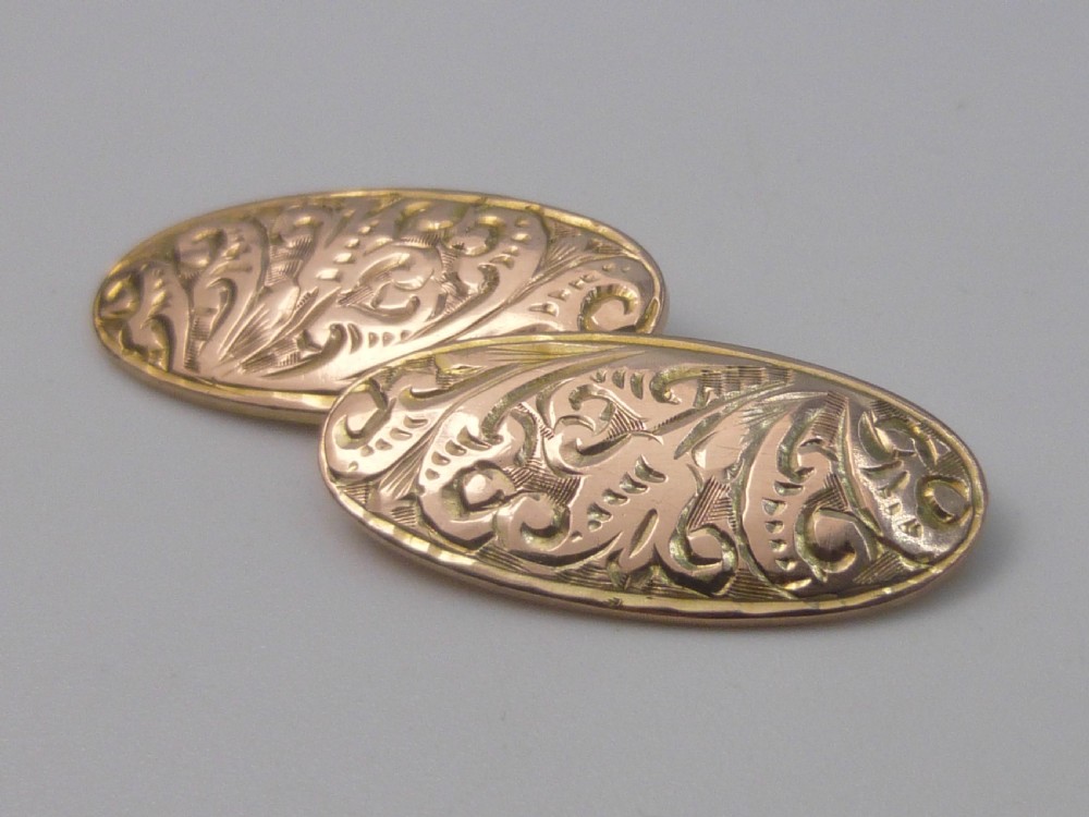 A set of four Edwardian nine-carat rose gold oval cufflink faces with hand-engraved scrollwork motifs. View IV