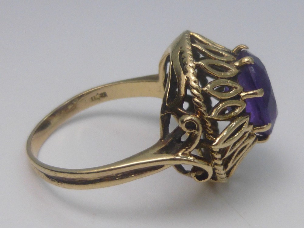 A gold dress ring featuring an oval facet-cut purple amethyst gemstone surrounded by a pierced openwork petal border. View III