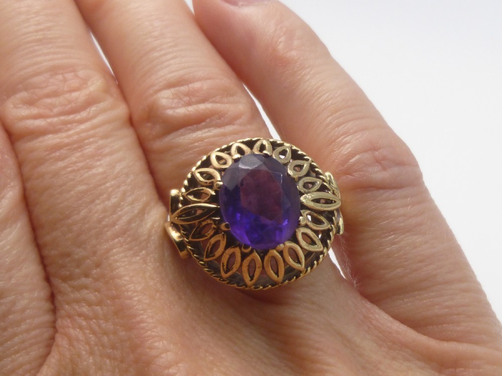 A gold dress ring featuring an oval facet-cut purple amethyst gemstone surrounded by a pierced openwork petal border. View IV