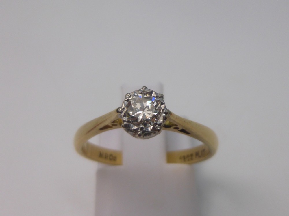 A yellow gold solitaire ring featuring a single round brilliant-cut diamond held in a white metal claw setting. View II