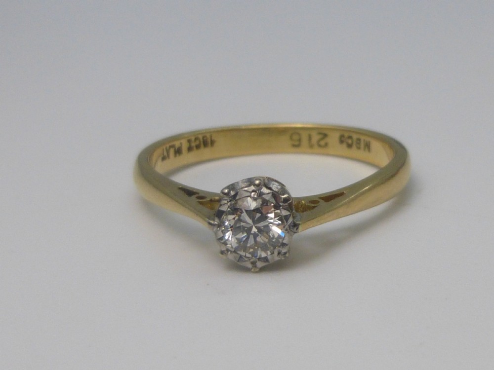 A yellow gold solitaire ring featuring a single round brilliant-cut diamond held in a white metal claw setting. View III