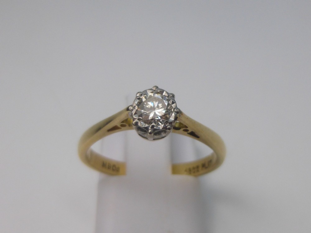 A yellow gold solitaire ring featuring a single round brilliant-cut diamond held in a white metal claw setting. View V