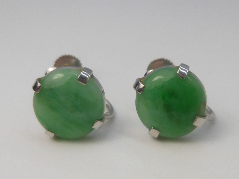 Pair of round green jadeite cabochon earrings set in four-prong white gold mounts with screw-back fittings.