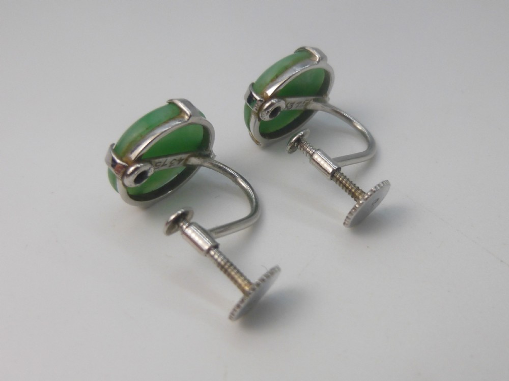 Pair of round green jadeite cabochon earrings set in four-prong white gold mounts with screw-back fittings. View V