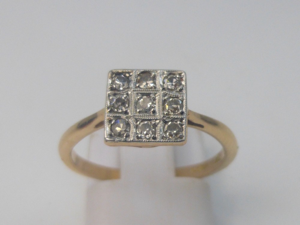 An Edwardian ring featuring a square setting containing nine diamonds in a three-by-three grid atop an 18ct yellow gold band.