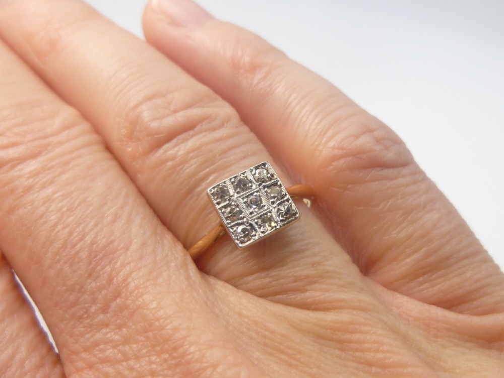 An Edwardian ring featuring a square setting containing nine diamonds in a three-by-three grid atop an 18ct yellow gold band. View II
