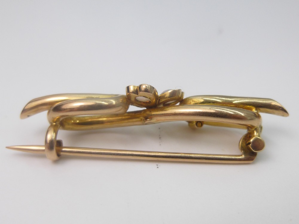 An Edwardian 15ct gold brooch featuring three cabochon opals arranged in a clover setting atop an intertwined gold loop design. View III