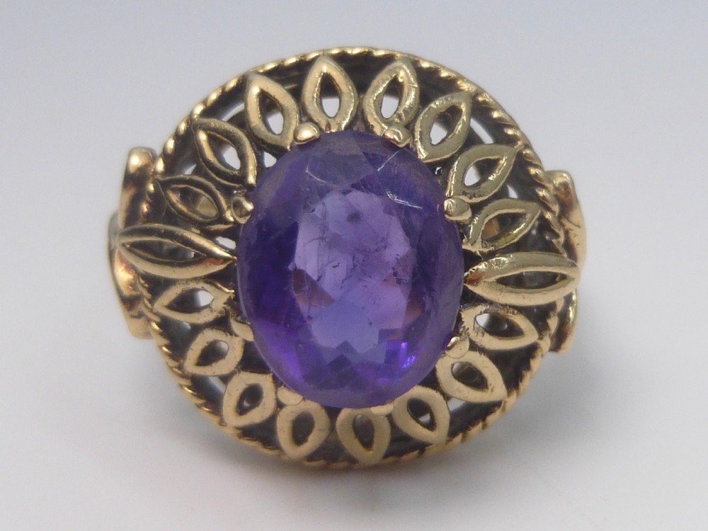 A gold dress ring featuring an oval facet-cut purple amethyst gemstone surrounded by a pierced openwork petal border. View VII