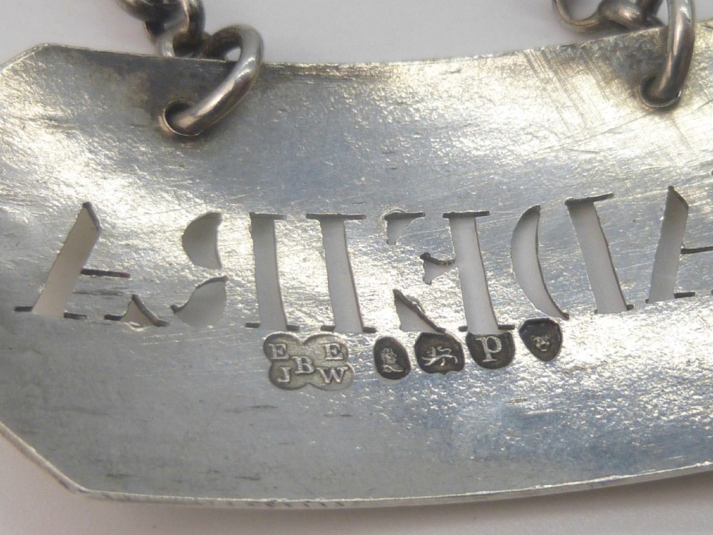 A rectangular William IV sterling silver decanter label with clipped corners engraved with the word Madeira and attached to a silver link chain. View V