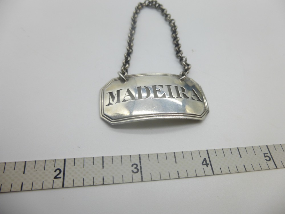 A rectangular William IV sterling silver decanter label with clipped corners engraved with the word Madeira and attached to a silver link chain. View XI