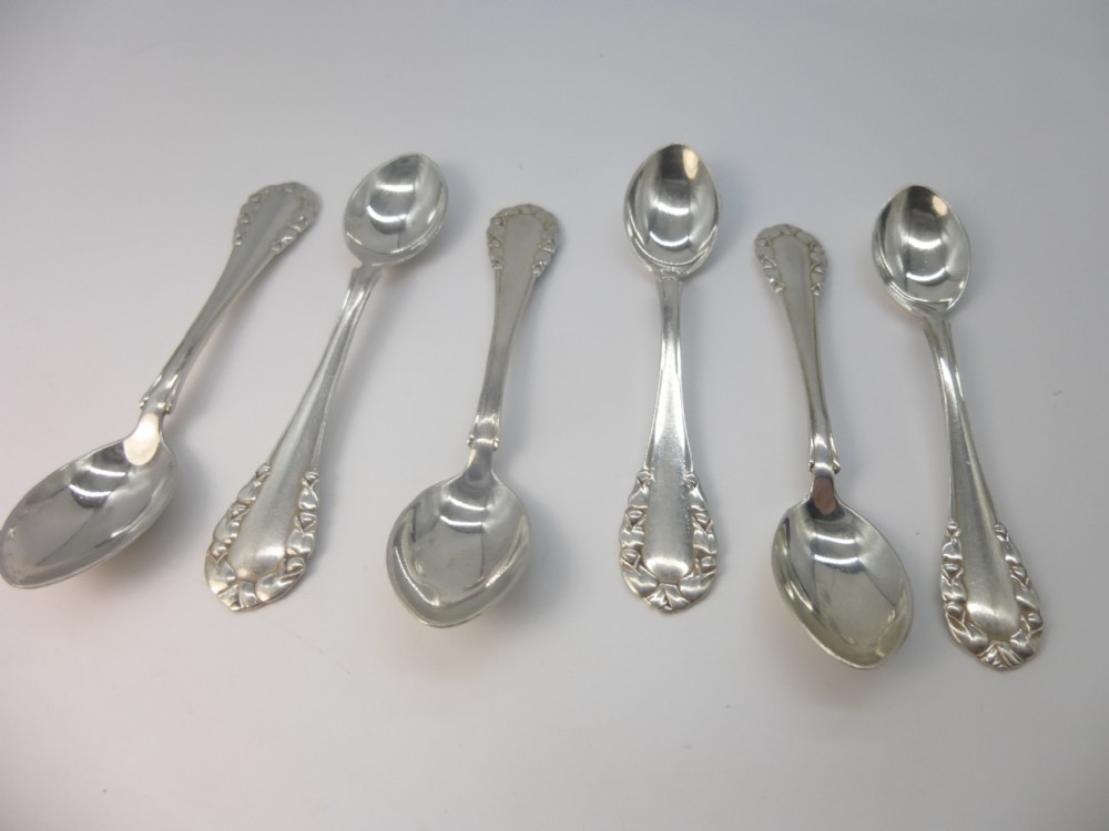 A set of six sterling silver Georg Jensen coffee spoons with relief borders on the handles displayed on a white background.