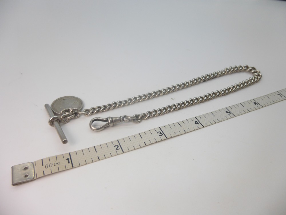 A sterling silver Albert pocket watch chain featuring curb links, a T-bar, a swivel clasp, and an attached silver coin fob against a plain background. View III