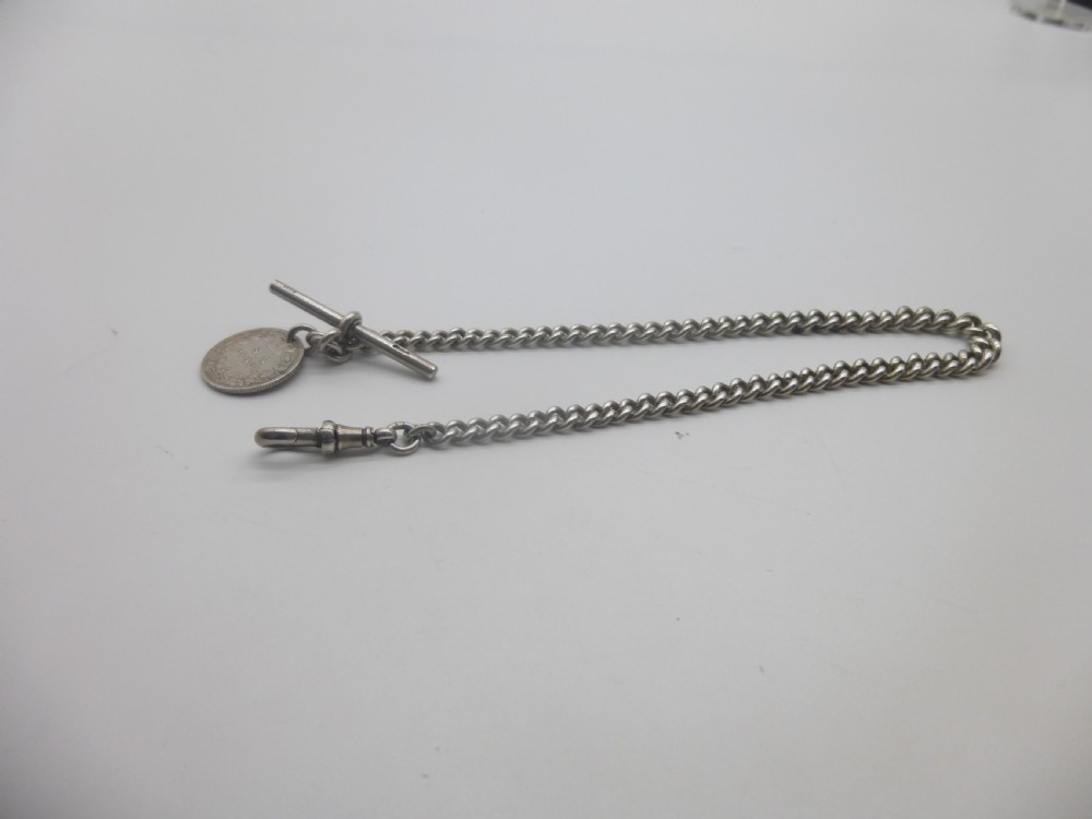A sterling silver Albert pocket watch chain featuring curb links, a T-bar, a swivel clasp, and an attached silver coin fob against a plain background. View IV