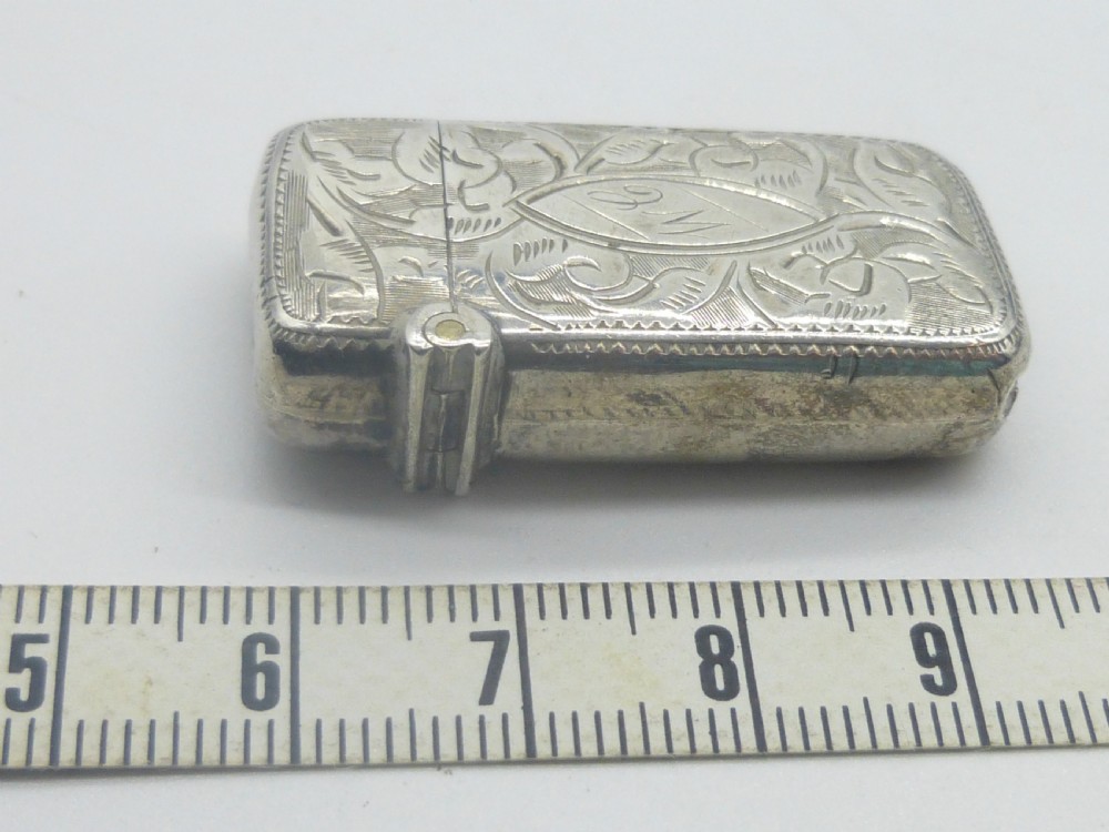 An antique silver vesta case featuring detailed foliate scroll engraving and a central oval monogrammed cartouche. View II