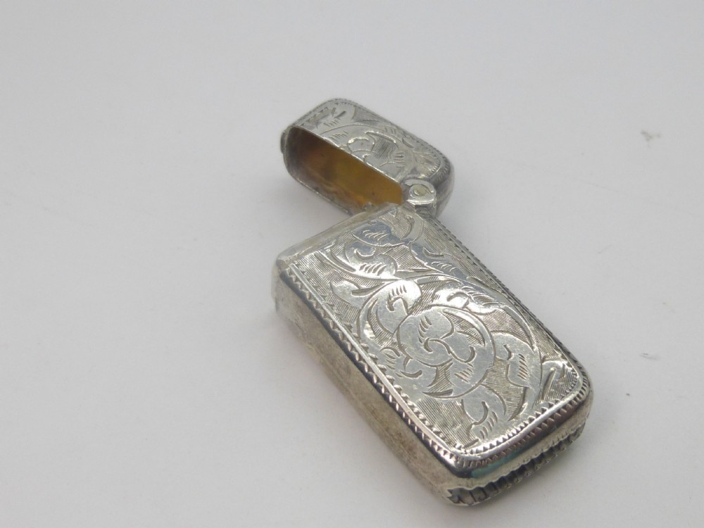 An antique silver vesta case featuring detailed foliate scroll engraving and a central oval monogrammed cartouche. View III