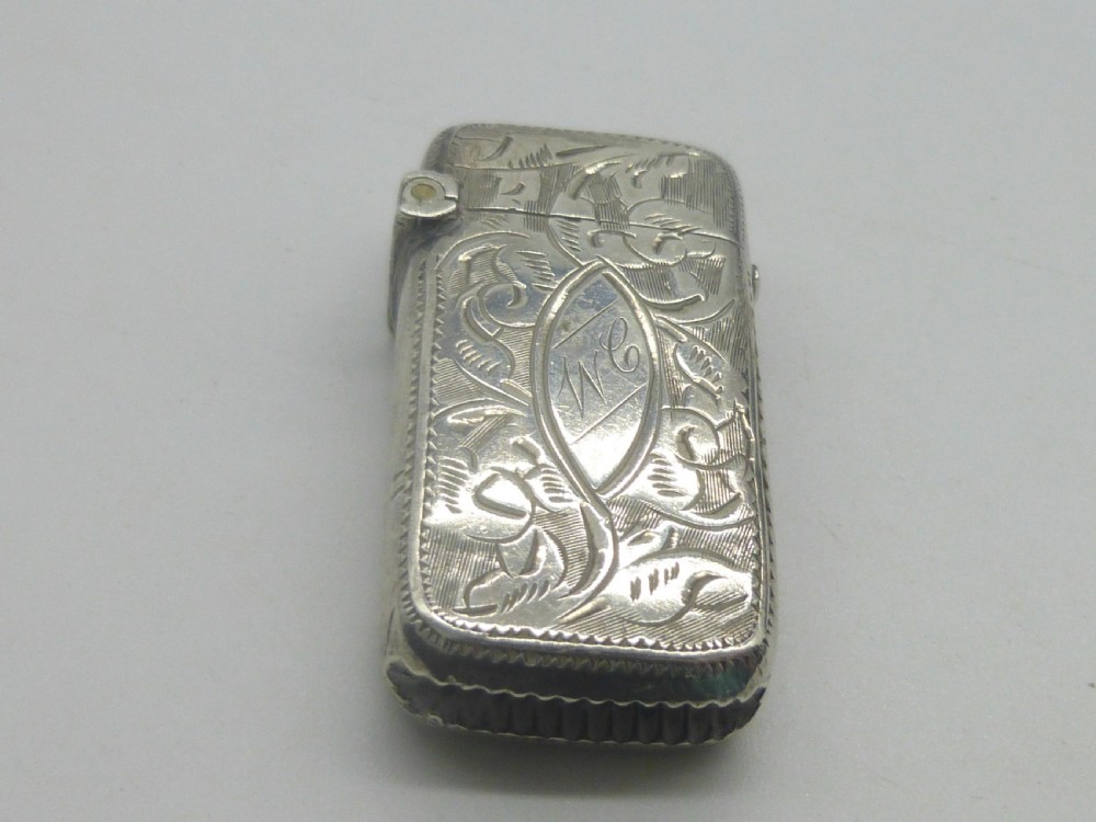 An antique silver vesta case featuring detailed foliate scroll engraving and a central oval monogrammed cartouche. View V