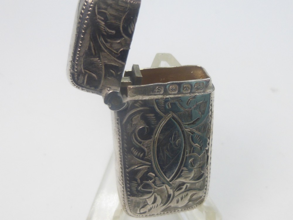 An antique silver vesta case featuring detailed foliate scroll engraving and a central oval monogrammed cartouche. View VI