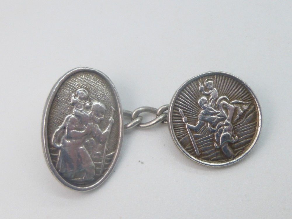 A pair of 1920s silver chain-link cufflinks featuring relief engravings of Saint Christopher on oval and circular faces. View II