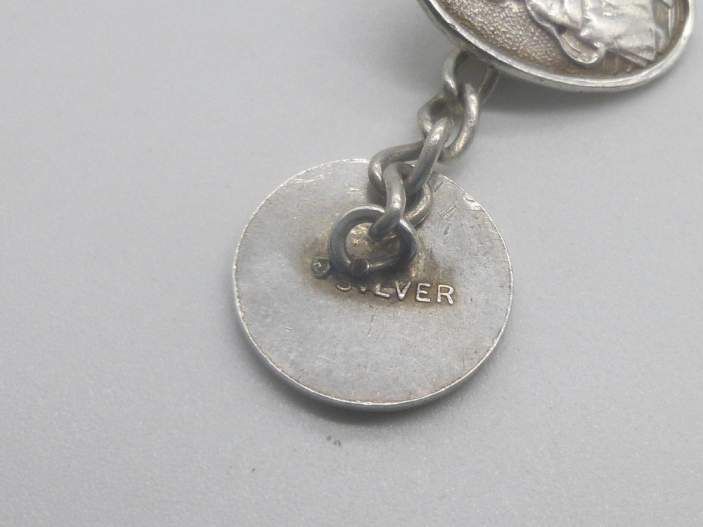 A pair of 1920s silver chain-link cufflinks featuring relief engravings of Saint Christopher on oval and circular faces. View III