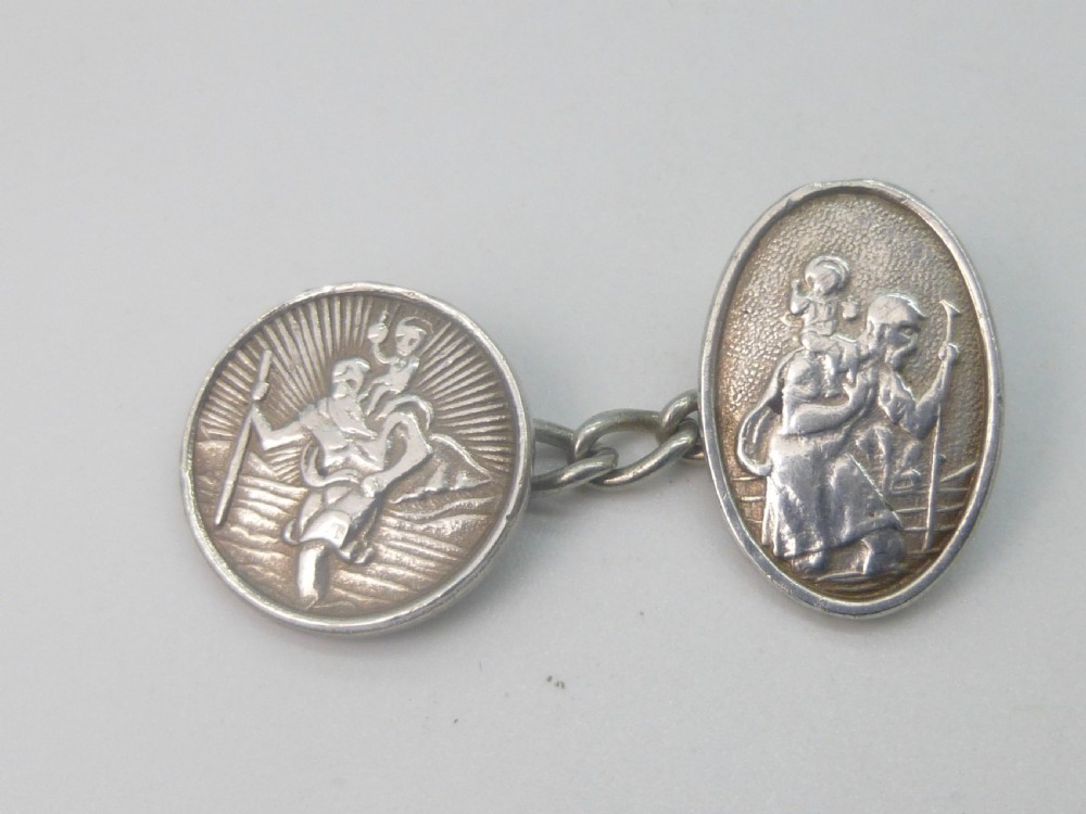 A pair of 1920s silver chain-link cufflinks featuring relief engravings of Saint Christopher on oval and circular faces. View IV