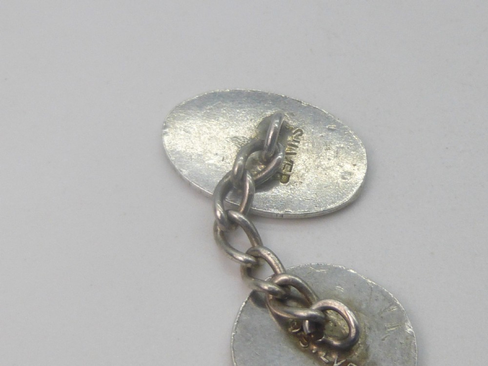 A pair of 1920s silver chain-link cufflinks featuring relief engravings of Saint Christopher on oval and circular faces. View V