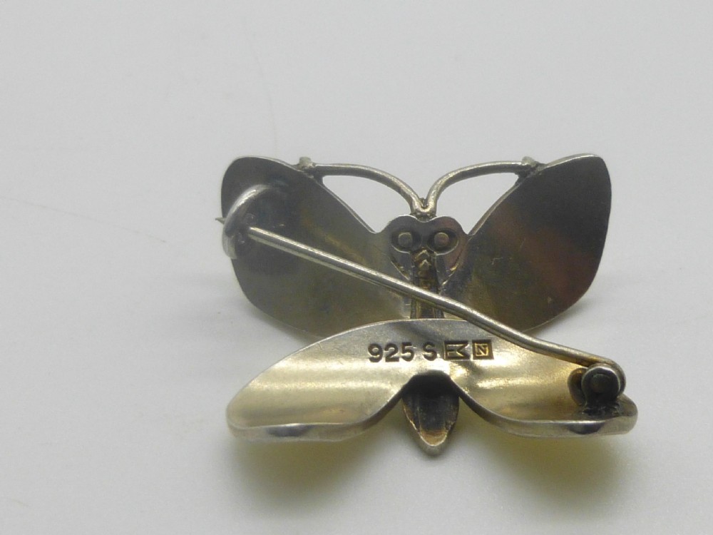 A silver butterfly brooch featuring yellow guilloche enamel wings, a green enamelled body, and red accent eyes. View V