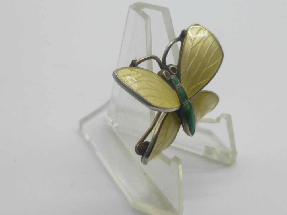 A silver butterfly brooch featuring yellow guilloche enamel wings, a green enamelled body, and red accent eyes. View VI