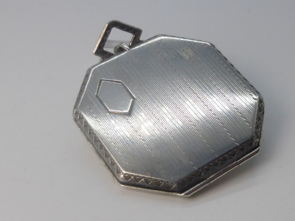 An octagonal Art Deco silver locket featuring engine-turned linear pattern, a hexagonal central cartouche, and a square top bail.